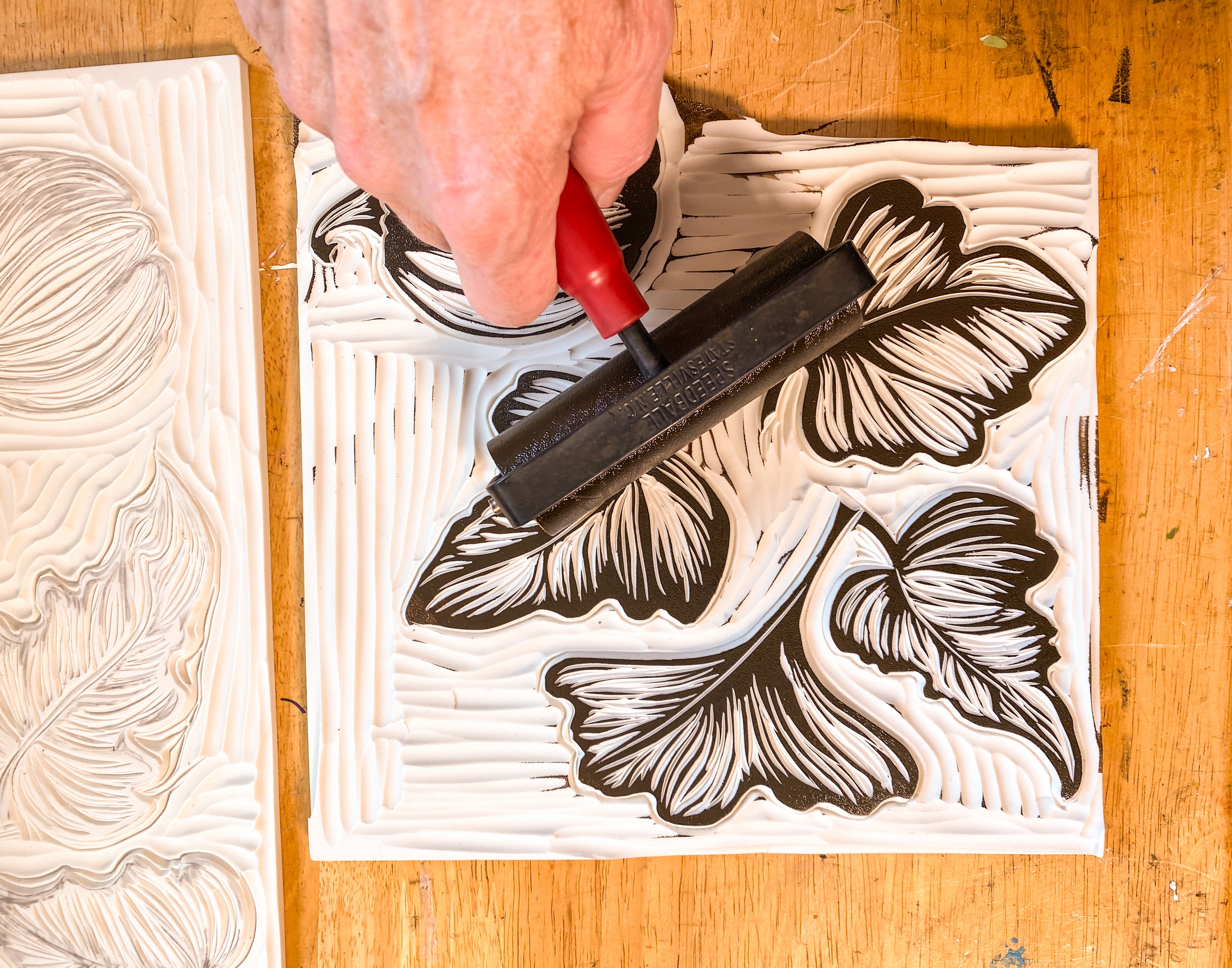 Hand rolling ink on a leaf-themed printing plate